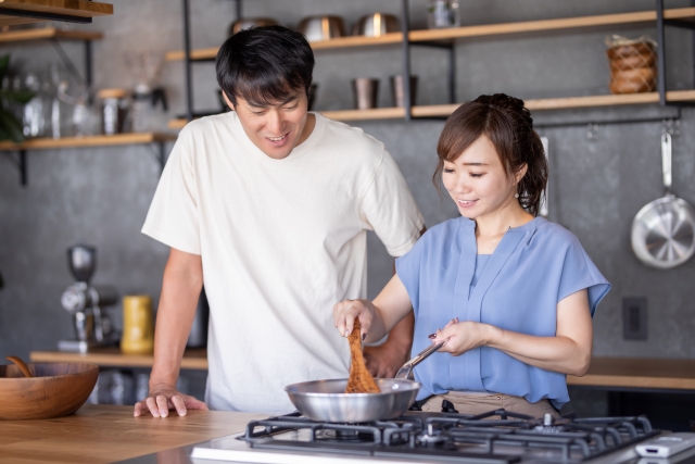 フライパンで料理をする夫婦